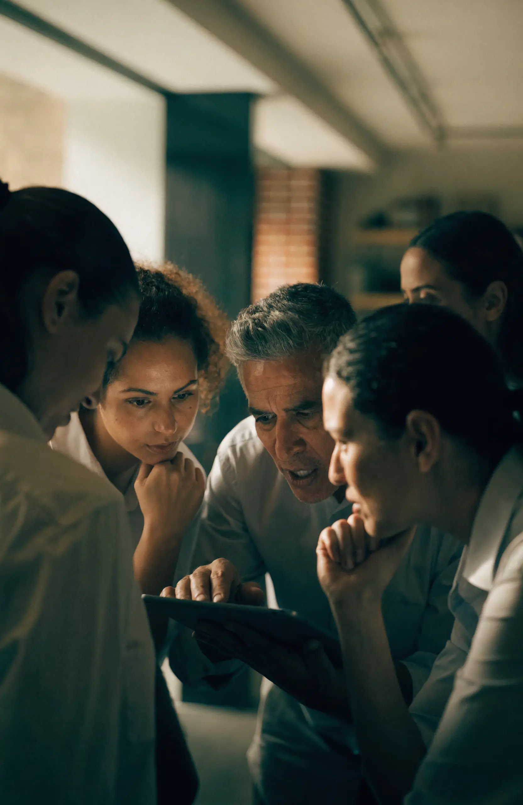 A hotel operations team collaborating around a tablet in a back-of-house space