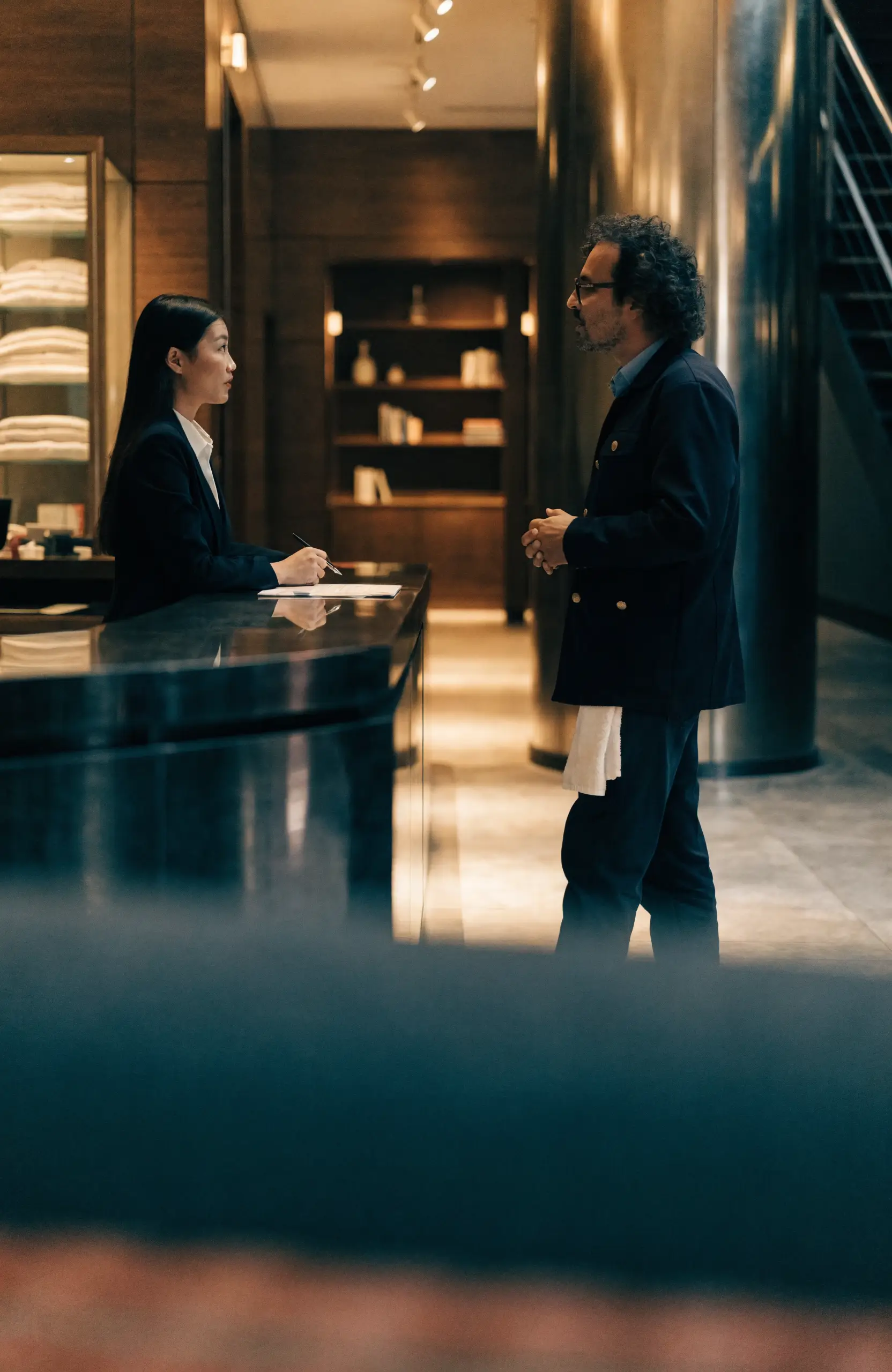A front-desk receptionist and a housekeeping supervisor talking in a hotel lobby